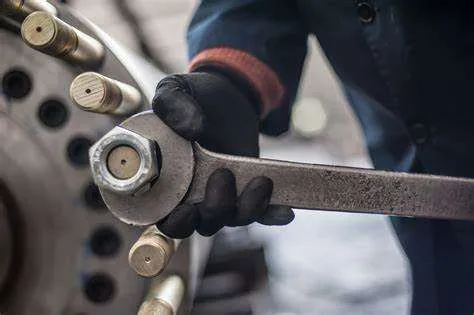 Technicien serrant un écrou à la clé sur un équipement industriel